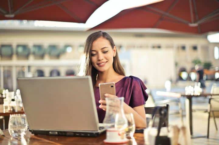 Person sitting at table on laptop looking at phone
